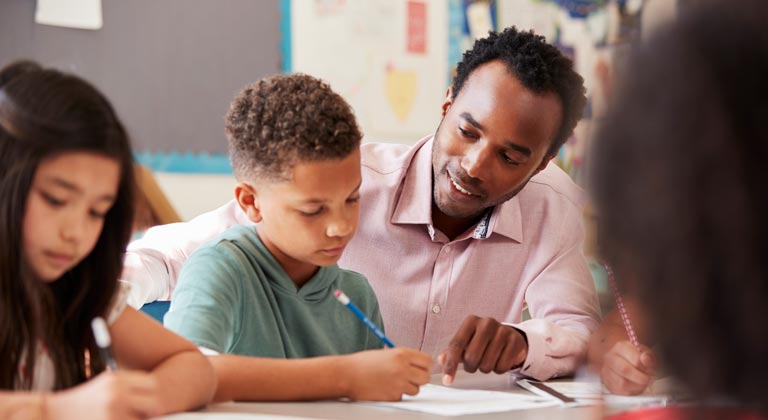 male teacher helping student at desk