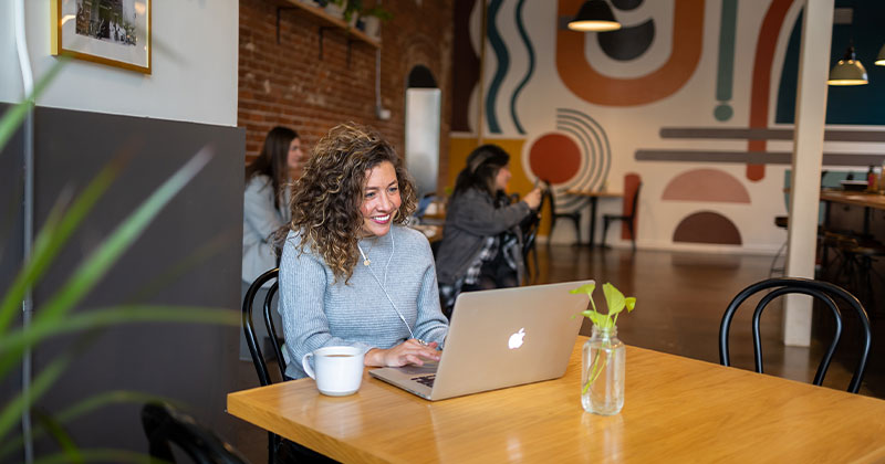 women in coffee shop smiling at laptop