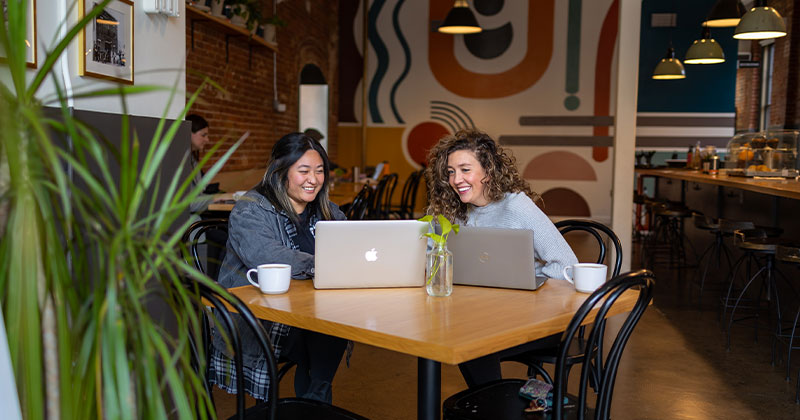 women at table with laptops